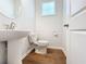 Cozy half bathroom with a pedestal sink, modern toilet, and wood-look tile flooring at 2560 Quarterdeck Dr, Cumming, GA 30041