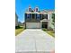 Charming two-story townhome features a gray brick facade, well-maintained lawn, and a three car garage at 2560 Quarterdeck Dr, Cumming, GA 30041
