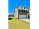 Well-manicured lawn compliments this townhome featuring a three car garage, and stone and siding exterior at 2560 Quarterdeck Dr, Cumming, GA 30041