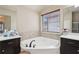 Bright bathroom with soaking tub beneath a window, flanked by dark cabinets and vanity sinks at 2126 Roberts View Trl, Buford, GA 30519