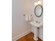 Classic pedestal sink and oval mirror add charm to this well-lit half bathroom with wood flooring at 1175 Glenridge Pl, Atlanta, GA 30342