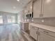 Kitchen with gray cabinets, stainless steel microwave, tiled backsplash, countertops, and an open view to the adjacent dining area at 3154 Rosebud Rd, Loganville, GA 30052