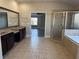 Bathroom featuring tile floors, double vanity, shower, and soaking tub in a neutral color palette at 3988 Two Bridge Drive, Buford, GA 30519