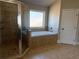 Bathroom with a glass-enclosed shower and garden tub with tile surround at 3988 Two Bridge Drive, Buford, GA 30519