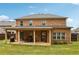 Back of a two-story brick home with a covered patio and outdoor dining area at 244 Lotus Cir, Mcdonough, GA 30252