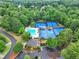 An aerial view of a community pool, multiple blue tennis courts, a clubhouse, surrounded by lush greenery at 607 Delphinium Nw Blvd, Acworth, GA 30102