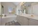 Bright bathroom with double sinks, white cabinets and tub under a window at 231 Beechwood Ln, Stone Mountain, GA 30087