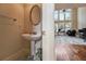 Elegant powder room with pedestal sink, decorative mirror, and adjoining room at 1132 Venetian Ln, Hampton, GA 30228