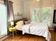 The bright bedroom features hardwood floors, a bright yellow side table, and large windows at 1247 Monroe Ne Dr, Atlanta, GA 30306