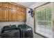 Functional laundry room with a modern washer and dryer, cabinet storage, and a bright window at 3231 Boulder Brook Dr, Lithonia, GA 30038