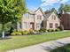 Charming two-story brick home with manicured lawn, mature tree, and red accents against a beautiful blue sky at 4070 Preserve Crossing Ln, Cumming, GA 30040