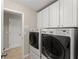 Bright laundry room with white cabinetry and modern front-loading washer and dryer at 4070 Preserve Crossing Ln, Cumming, GA 30040