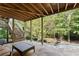 Covered patio with stone flooring, stairs to deck, and wooded backyard view at 4070 Preserve Crossing Ln, Cumming, GA 30040