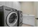 Modern laundry room with front loading washer and dryer plus a utility sink with white cabinets at 351 Allendale Dr, Canton, GA 30115