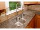 Close-up of a stainless steel kitchen sink with a view from the window of the greenery outside at 4144 Hideaway Dr, Tucker, GA 30084