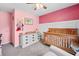 Charming pink Bedroom with a crib and dresser, offering a serene space for your little one at 113 Emerald Pines Dr, Dallas, GA 30157