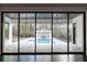 Expansive sliding glass doors opening to an outdoor pool, cabana, and landscaped backyard at 5211 Powers Ferry Rd, Sandy Springs, GA 30327