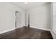 An empty bedroom with hardwood floors, white walls and trim, with open doors to other rooms at 7285 Cordery Rd, Cumming, GA 30040