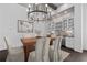 Dining room with a wooden table, white chairs, chandelier, and a built in bar with glass-front cabinets at 7285 Cordery Rd, Cumming, GA 30040