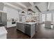 Open kitchen with white cabinets, gray island, stainless appliances, hardwood floors, and open to the living room at 7285 Cordery Rd, Cumming, GA 30040