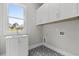 The laundry room boasts patterned floor tile, bright light, and a stainless steel sink at 7285 Cordery Rd, Cumming, GA 30040