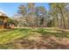 Expansive backyard featuring a manicured lawn, mature trees, and a covered patio area perfect for outdoor entertaining at 8078 Longleaf Dr, Villa Rica, GA 30180