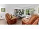 Cozy living room features a bay window, hardwood floors, plant shelf, and comfortable leather seating at 8078 Longleaf Dr, Villa Rica, GA 30180