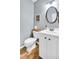 Half bathroom featuring gray walls, a white vanity with black knobs, and wood look floors at 44 Hall Mnr, Alpharetta, GA 30022