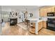 Open kitchen with wood floors, stainless appliances, and a view of the fireplace and dining area at 44 Hall Mnr, Alpharetta, GA 30022