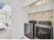Convenient laundry room featuring a new washer and dryer, upper cabinets, and floral wallpaper at 44 Hall Mnr, Alpharetta, GA 30022