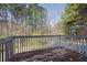 Wooden deck overlooks the backyard surrounded by a lush green space and many mature trees at 6595 Lancelot Ct, Riverdale, GA 30296