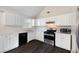 Well-lit kitchen with white cabinets, stainless steel appliances, and dark wood-look flooring at 6595 Lancelot Ct, Riverdale, GA 30296
