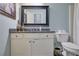 Well-lit bathroom vanity with dark granite countertop, large mirror, and white cabinetry at 480 Firelite Ln, Suwanee, GA 30024