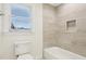 Modern bathroom with a white toilet and tile surround bathtub with a storage nook at 5960 Magnolia Rdg, Stone Mountain, GA 30087