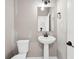 Bathroom featuring a pedestal sink, a toilet, and a wall mirror at 61 Okeechobee Way, Braselton, GA 30548
