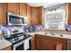 A well lit kitchen with stainless steel appliances, wooden cabinets, and tile backsplash at 6355 Queens Rd, Douglasville, GA 30135