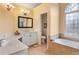 Bright bathroom featuring double sinks, tub, and a large window providing natural light at 755 Creek Wind Ct, Johns Creek, GA 30097