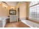Bathroom featuring double sinks, tub, large window, and tile floors at 755 Creek Wind Ct, Johns Creek, GA 30097