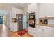 Spacious kitchen boasts stainless steel appliances, white cabinetry, and hardwood floors leading to the front entry at 755 Creek Wind Ct, Johns Creek, GA 30097