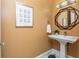 Stylish powder room featuring a pedestal sink, unique mirror and artwork, and black and white tile flooring at 3280 Stillhouse Se Ln # 108, Atlanta, GA 30339