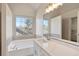 Bright bathroom featuring a soaker tub under a window, a long vanity, and a walk-in closet at 275 Carriage Chase, Fayetteville, GA 30214