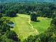 Aerial view of the golf course with a winding path, pond, and surrounding trees at 49 Inverness Ct, Hiram, GA 30141