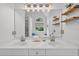 Bright bathroom featuring double sinks, large mirror, and wooden shelves at 49 Inverness Ct, Hiram, GA 30141