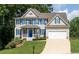 Charming two-story home with a well-manicured lawn, a blue front door, and an attached garage at 49 Inverness Ct, Hiram, GA 30141