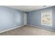 Well-lit bedroom featuring neutral carpet, light-blue walls, and a window at 6005 Pattingham Dr, Roswell, GA 30075