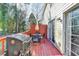 Red wooden back deck featuring an outdoor grill, table, and chairs next to house with sliding glass door at 4008 Bayside Cir, Atlanta, GA 30340