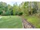 Beautiful backyard with mature trees and a rock-lined drainage path or stream bed at 203 Glenrise Ct, Woodstock, GA 30188