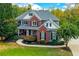 Two-story home boasts a beautiful lawn, landscaping, and a long driveway amid a lush and private wooded property at 203 Glenrise Ct, Woodstock, GA 30188