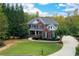 Two-story home boasts a beautiful lawn, landscaping, and a long driveway amid a lush and private wooded property at 203 Glenrise Ct, Woodstock, GA 30188