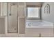 Clean, bright bathroom featuring a glass door shower and a soaking tub beneath a frosted window at 112 Bluestone Ct, Acworth, GA 30101